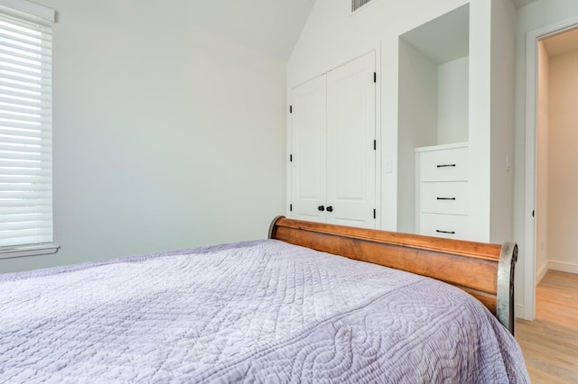 bedroom with lofted ceiling, light hardwood / wood-style floors, and a closet