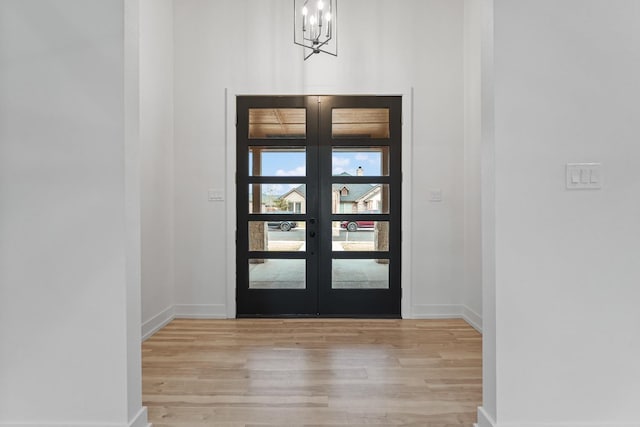 entrance foyer featuring french doors, an inviting chandelier, and light hardwood / wood-style floors