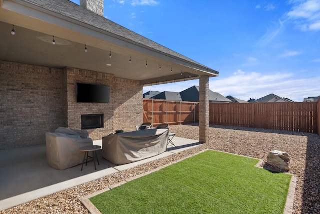 view of yard featuring an outdoor brick fireplace and a patio