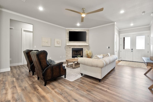 living room featuring hardwood / wood-style flooring, ornamental molding, ceiling fan, and a fireplace