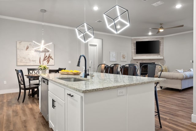 kitchen with pendant lighting, stainless steel dishwasher, sink, and a kitchen island with sink