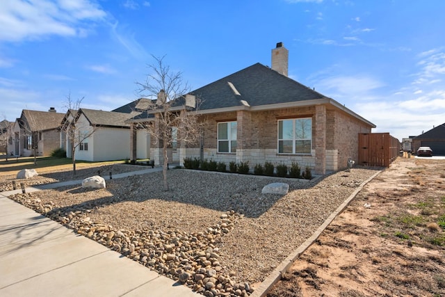 view of front of property with stone siding, a residential view, a chimney, and a shingled roof