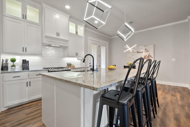 kitchen with white cabinetry, light stone countertops, sink, and a center island with sink