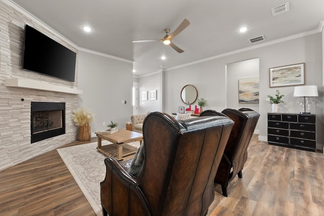 living room with hardwood / wood-style floors, a fireplace, ornamental molding, and ceiling fan