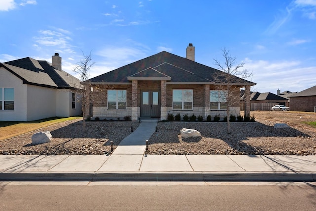 view of front of house with stone siding and a chimney