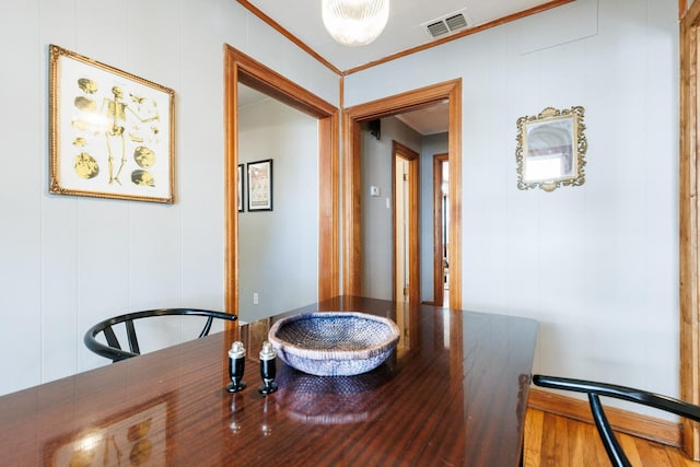 dining area with wood-type flooring and ornamental molding