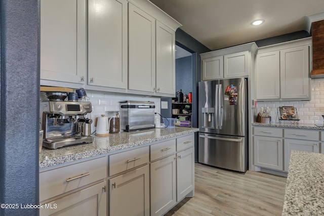 12010 N Crk 1500, Shallowater, TX 79363 - kitchen featuring stainless steel refrigerator with ice dispenser, tasteful backsplash, light wood-style floors, recessed lighting, and light stone counters