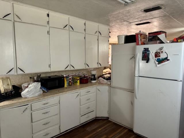 kitchen with white refrigerator, white cabinetry, and dark hardwood / wood-style floors