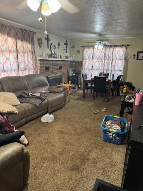 living room with a brick fireplace, ceiling fan, and carpet flooring