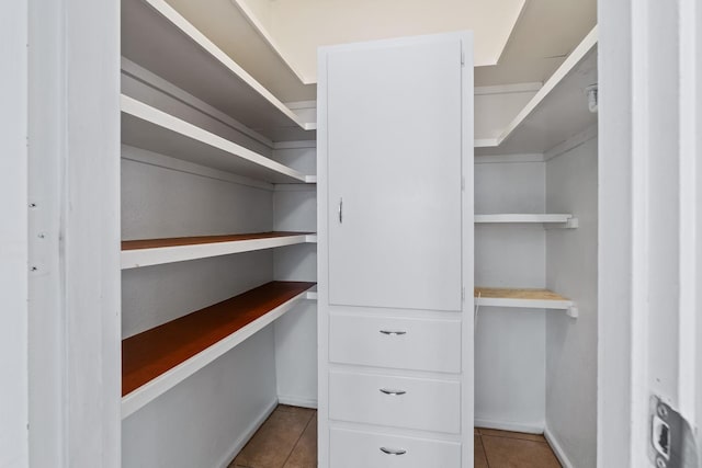 spacious closet featuring built in desk and light tile patterned floors