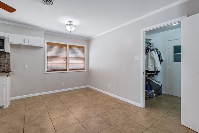 unfurnished dining area with light tile patterned floors, ornamental molding, and ceiling fan