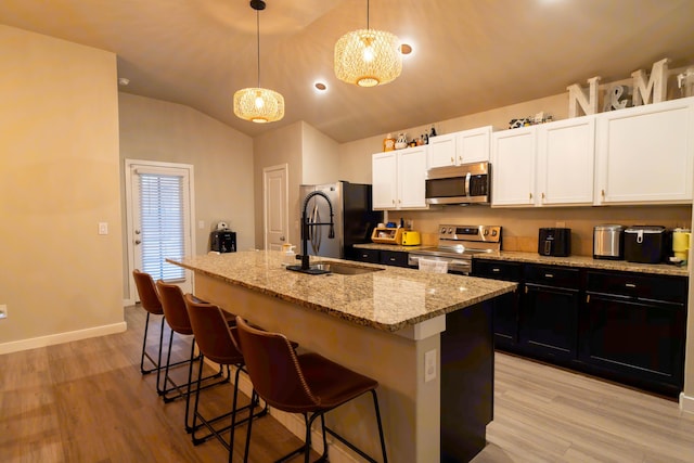 kitchen featuring pendant lighting, sink, stainless steel appliances, a kitchen breakfast bar, and a center island with sink