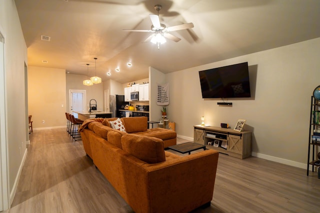 living room featuring lofted ceiling, sink, hardwood / wood-style floors, and ceiling fan