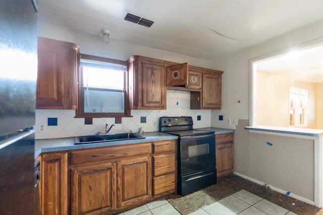 kitchen featuring stainless steel refrigerator, sink, decorative backsplash, light tile patterned floors, and electric range