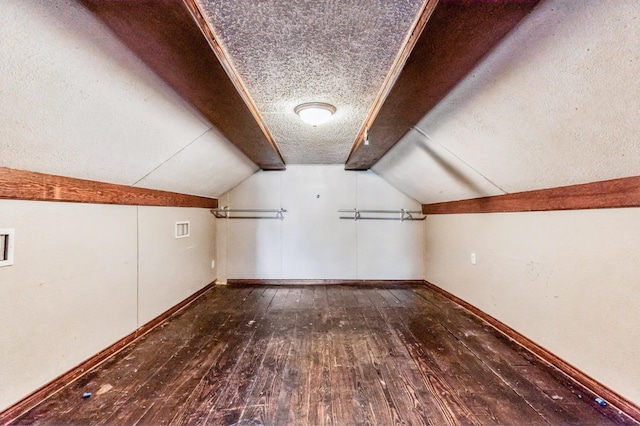 additional living space with dark hardwood / wood-style flooring, lofted ceiling, and a textured ceiling