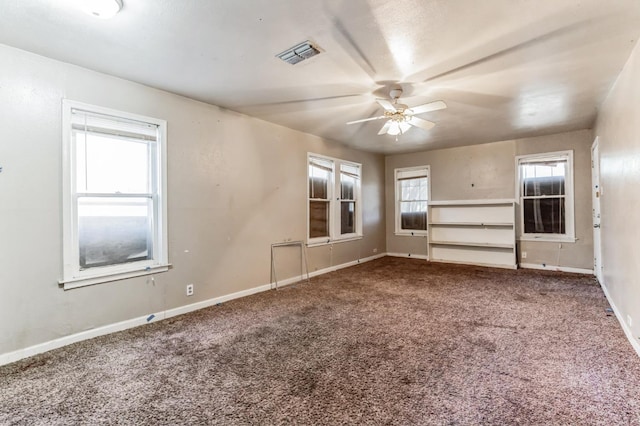 carpeted spare room featuring a healthy amount of sunlight and ceiling fan