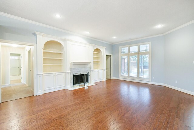 living room with crown molding, a fireplace, dark hardwood / wood-style flooring, and built in shelves