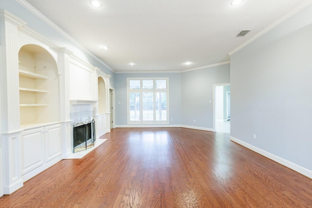 unfurnished living room with crown molding, built in shelves, and wood-type flooring