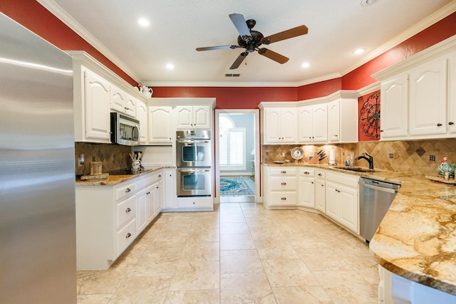 kitchen with sink, ornamental molding, stainless steel appliances, light stone countertops, and white cabinets