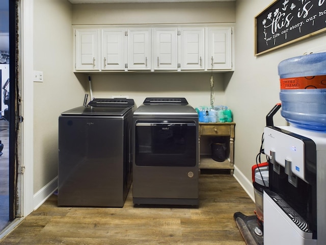 clothes washing area with cabinets, washer and clothes dryer, and hardwood / wood-style floors