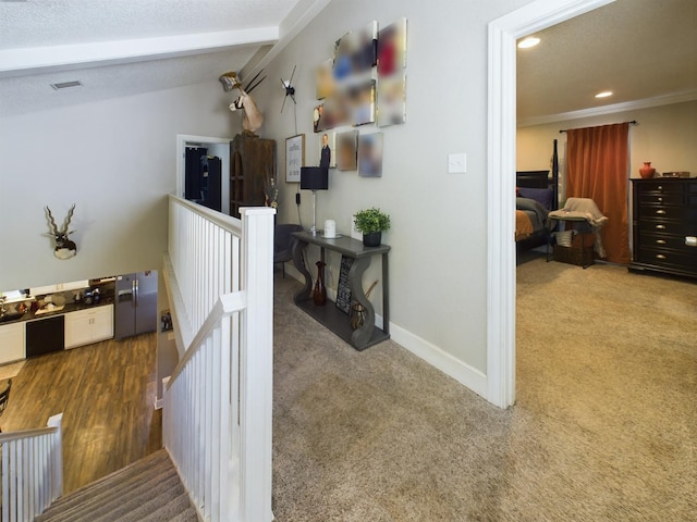 corridor with ornamental molding, lofted ceiling with beams, a textured ceiling, and carpet flooring