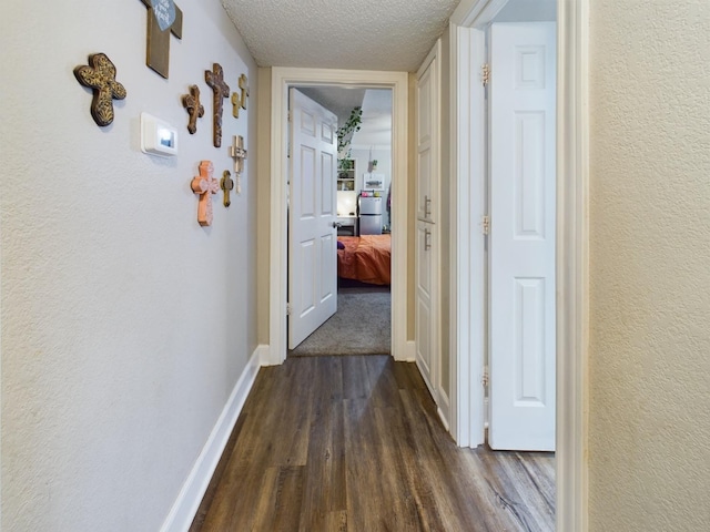 hall featuring dark wood-type flooring and a textured ceiling