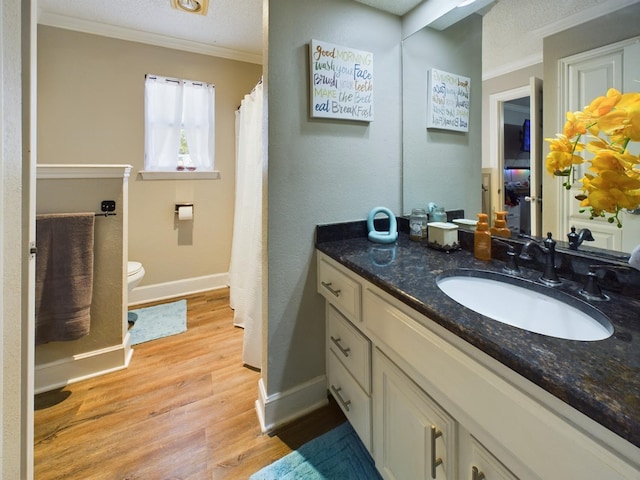 bathroom featuring wood-type flooring, vanity, ornamental molding, toilet, and a textured ceiling