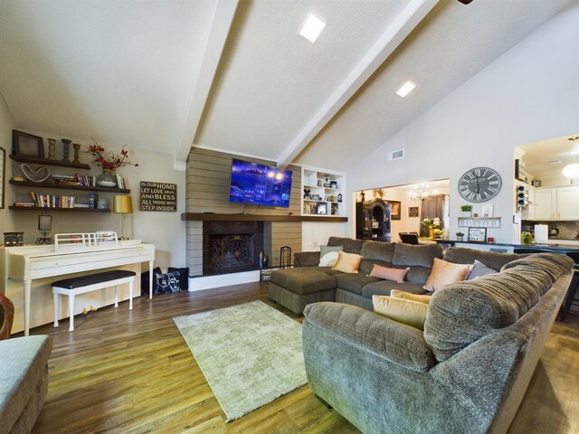 living room with high vaulted ceiling, dark hardwood / wood-style flooring, a notable chandelier, a brick fireplace, and beam ceiling