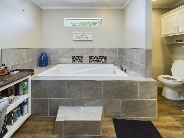 bathroom with ornamental molding, toilet, hardwood / wood-style floors, and tiled tub