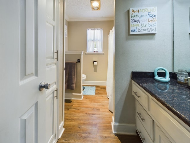 bathroom with hardwood / wood-style floors, vanity, ornamental molding, a textured ceiling, and toilet