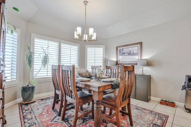 tiled dining space with an inviting chandelier and a tray ceiling