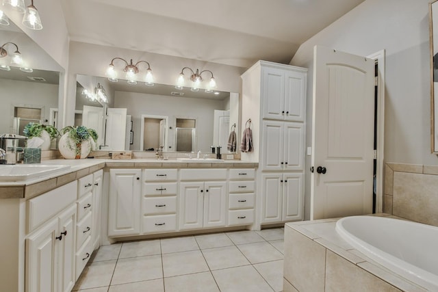 bathroom featuring vanity, tiled tub, vaulted ceiling, and tile patterned floors