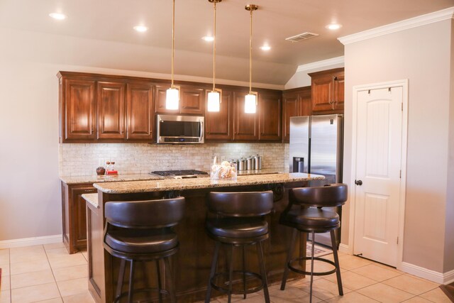 kitchen featuring a kitchen bar, hanging light fixtures, a center island, stainless steel appliances, and light stone countertops