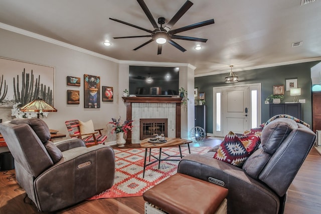 living room featuring crown molding, hardwood / wood-style floors, ceiling fan, and a fireplace