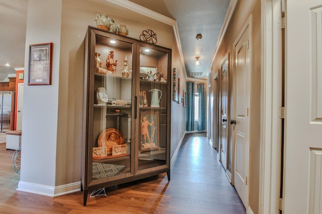 corridor with ornamental molding, wood-type flooring, and a textured ceiling