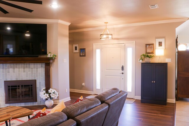 living room with dark wood-type flooring, a fireplace, crown molding, and ceiling fan