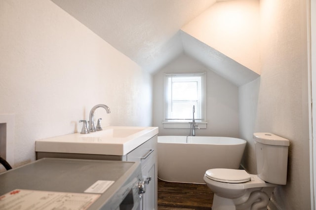 bathroom featuring lofted ceiling, toilet, wood-type flooring, vanity, and a washtub