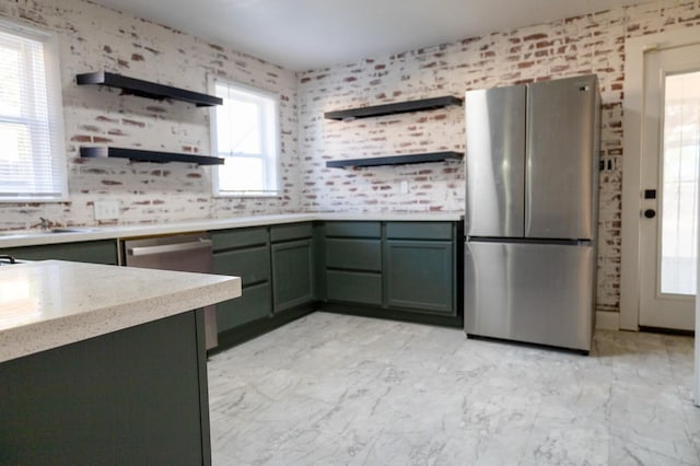 kitchen with brick wall, appliances with stainless steel finishes, and green cabinets