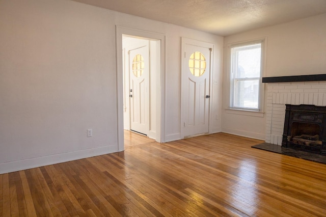 unfurnished living room featuring a fireplace, a textured ceiling, and light wood-type flooring