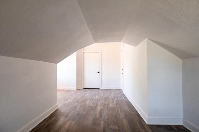 bonus room with dark wood-type flooring and vaulted ceiling