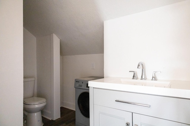 bathroom featuring hardwood / wood-style flooring, vanity, washer / dryer, vaulted ceiling, and toilet