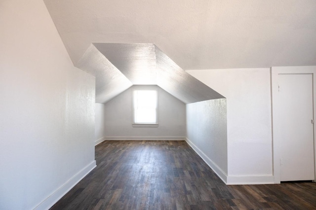 bonus room featuring dark hardwood / wood-style floors, vaulted ceiling, and a textured ceiling