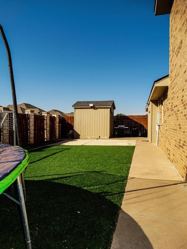 view of yard featuring a shed, a trampoline, and a patio area