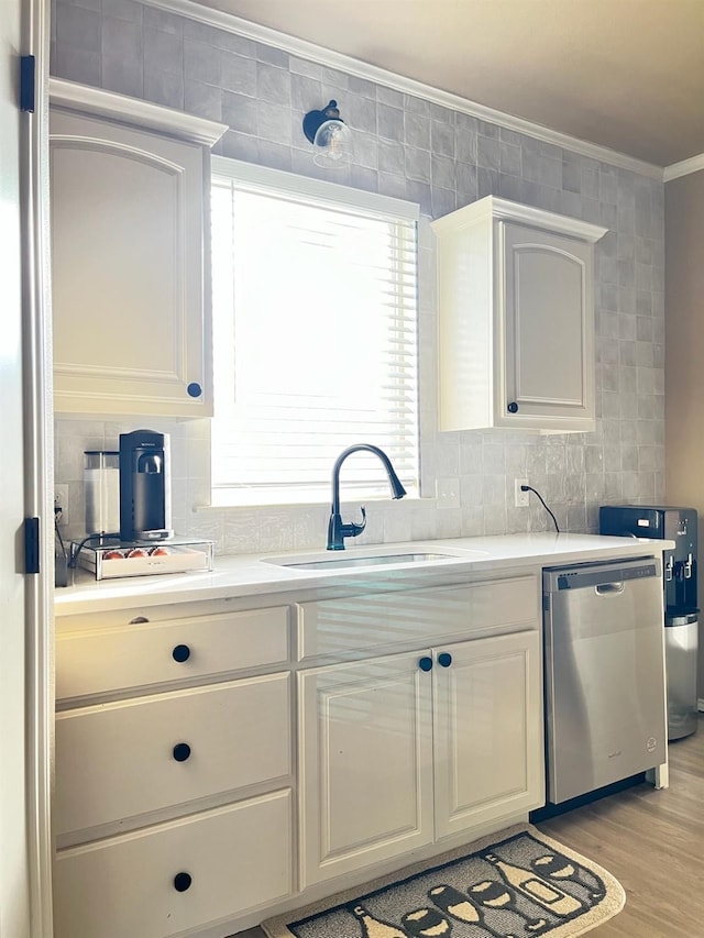 kitchen with white cabinetry, dishwasher, sink, decorative backsplash, and crown molding