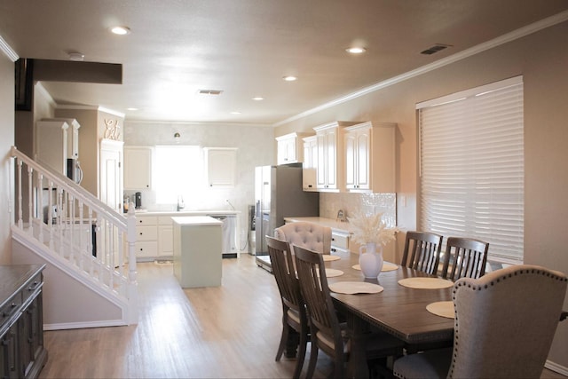 dining space featuring crown molding and light wood-type flooring