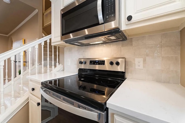 kitchen with tasteful backsplash, white cabinetry, appliances with stainless steel finishes, and crown molding