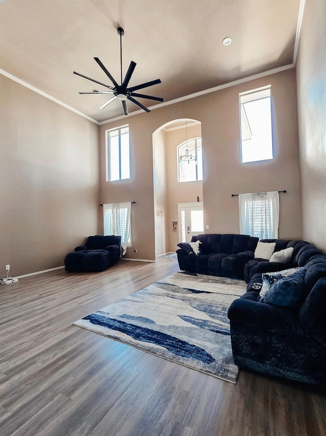 living room featuring hardwood / wood-style floors, ornamental molding, ceiling fan, and a high ceiling