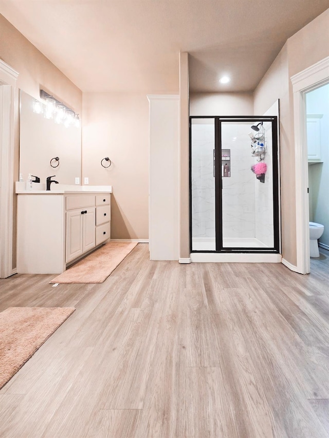 bathroom with hardwood / wood-style flooring, vanity, and a shower with door