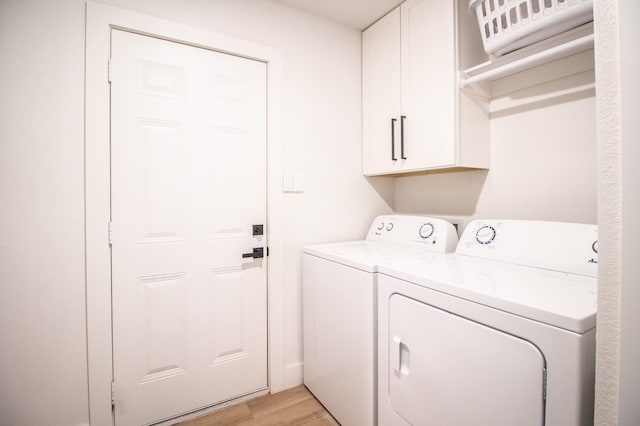 washroom featuring separate washer and dryer, cabinets, and light wood-type flooring