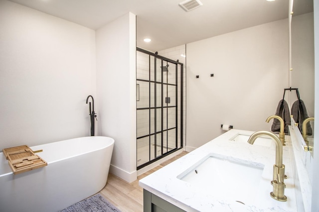 bathroom featuring vanity, hardwood / wood-style flooring, and plus walk in shower